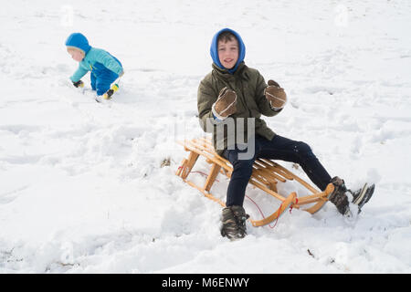 Garçon de huit ans et son frère âgé de 18 mois. La luge ou de la luge dans la neige , Medstead, Alton, Hampshire, Angleterre, Royaume-Uni. Banque D'Images