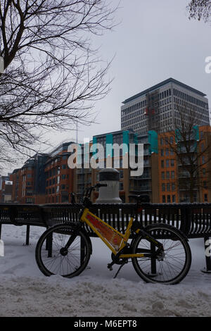 Une location de vélo à Bristol's YoBike système britannique en appui sur un banc à Cannons Marsh, dans la neige de tempête Emma Banque D'Images