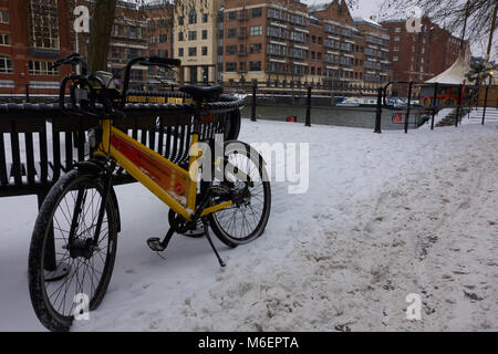 Une location de vélo à Bristol's YoBike système britannique en appui sur un banc à Cannons Marsh, dans la neige de tempête Emma Banque D'Images