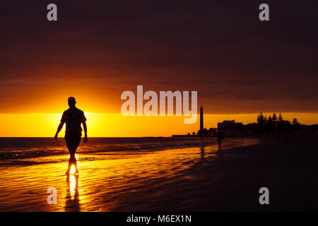 Walker sur mer avec phare au coucher du soleil à Maspalomas, Gran Canaria Island. Banque D'Images