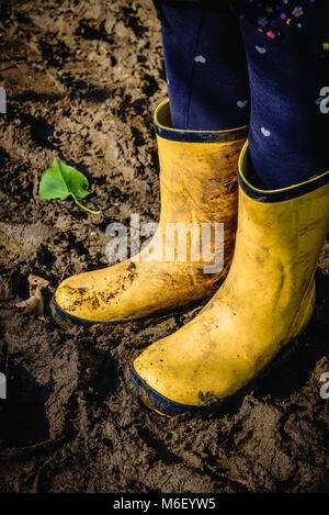 Jaune sale children's wellies dans la boue en hiver Banque D'Images