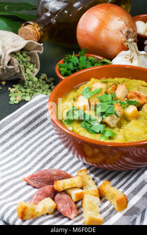 Split pea soup dans à décor rustique avec des feuilles vertes,l'ail, l'oignon et les tranches de lard Banque D'Images