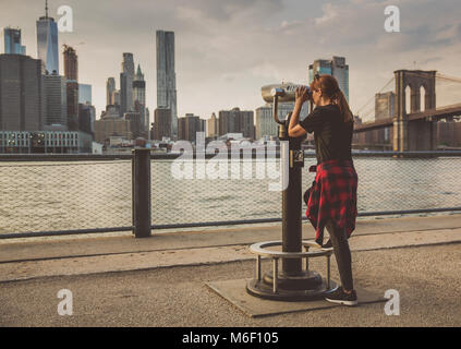 Les femmes à la recherche de New York à travers un télescope Banque D'Images