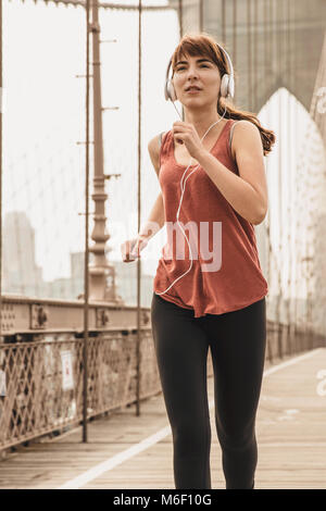 Femme pratiquant le jogging sur le pont de Brooklyn Banque D'Images