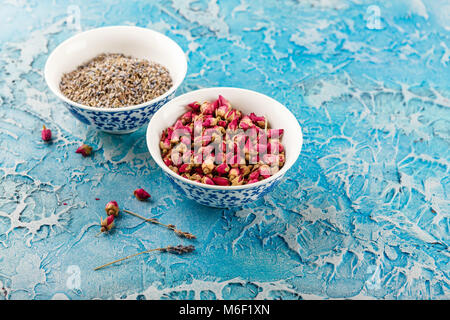 Assortiment d'herbes médicinales à sec les bourgeons roses et la lavande dans des bols. Banque D'Images