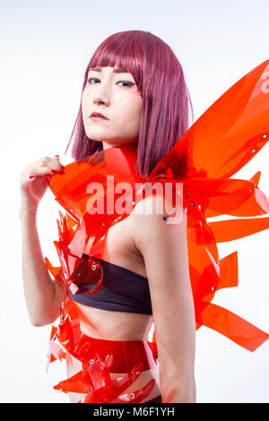 Asian woman cosplayeuse avec costume futuriste en rouge, faite de pvc et plastiques transparents. orientale Banque D'Images