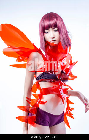 Asian woman cosplayeuse avec costume futuriste en rouge, faite de pvc et plastiques transparents. orientale Banque D'Images