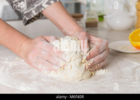 Close-up of female hands kneading dough dans cuisine minimaliste moderne. La préparation et le mélange la pâte. Banque D'Images