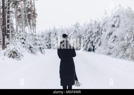 La fille de promenades et de pose sur la caméra à l'arrière-plan de la forêt d'hiver Banque D'Images