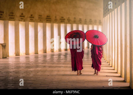 Deux moine novice tenant un parapluie rouge et de la marche dans la pagode, le Myanmar. Banque D'Images