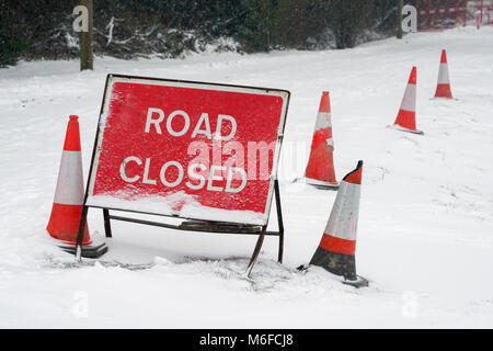 Un Red Road Closed sign et cônes couverts en neige fraîche sur une voie dans le Hampshire, en Angleterre. Prise le 2 mars 2018. Banque D'Images