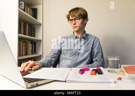 Personne de sexe masculin travaille avec des livres et un ordinateur portable sur accueil cession ou projet. Prise de vue au grand angle de beau jeune étudiant de lecture lunettes modernes au minim Banque D'Images