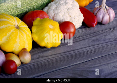 La nature morte de légumes de saison sur une table en bois rustique. L'espace pour votre texte. Courgette verte, tomate, courge jaune, chou-fleur, poivron rouge Banque D'Images