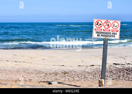 Un signe sur la plage de Swakopmund Namibie Afrique du Sud que les intrus seront poursuivis prises dans le soleil du matin à l'Océan Atlantique aga Banque D'Images