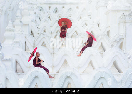 MANDALAY, MYANMAR, -le 11 décembre 2017 asiatique non identifié : jeune moine tenant un parapluie rouge sur la Mya Thein Tan Mingun pagode à Mandalay, Myanmar. Banque D'Images