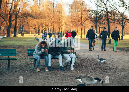 Munich, Allemagne, le 29 décembre 2016 : Les Amis s'asseoir sur un banc dans le Jardin Anglais de Munich l'un des plus grands parcs urbains au monde . Camping, la communication, l'amitié, l'excellent passe-temps. Banque D'Images