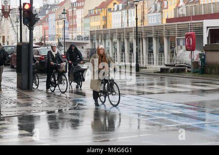 Copenhague - 23 octobre 2016 : Une vieille dame et d'autres personnes sur leurs vélos en attendant de traverser la rue au cours d'une pluie de Nyhavn. Banque D'Images