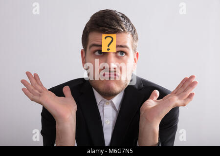 Close-up of a Young Businessman With Sticky Notes sur son front montrant des signes d'Interrogation Banque D'Images