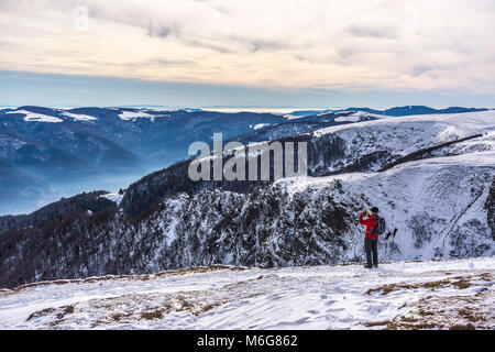 Un randonneur de prendre une photo avec son téléphone d'un magnifique paysage hivernal dans le massif des Vosges, Hohneck, France. Banque D'Images