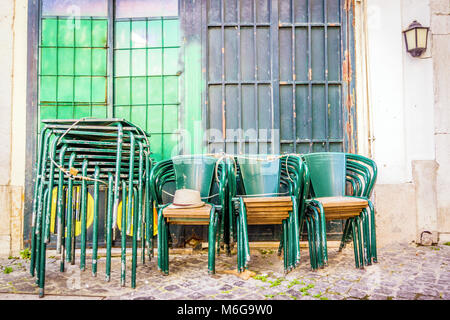 Empilés et verrouillé tables et chaises vert sur la vieille rue de Lisbonne, Portugal Banque D'Images