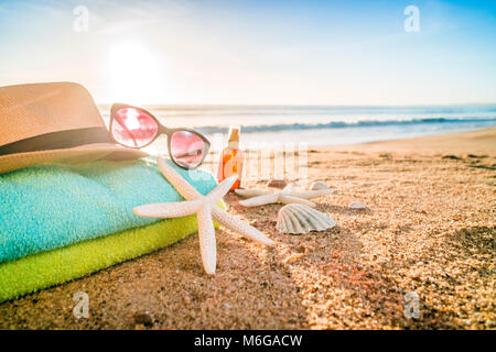 Accessoires d'été comme les lunettes, serviettes, chapeau, crème solaire, de coquillages et d'étoiles de mer sur la plage de sable au Portugal Banque D'Images