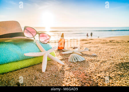 Accessoires d'été comme les lunettes, serviettes, chapeau, crème solaire, de coquillages et d'étoiles de mer sur la plage de sable au Portugal Banque D'Images