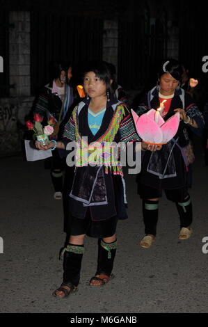 Les jeunes professionnels et jeunes filles Hmong solennelle habillés en vêtements traditionnels des bougies et des fleurs pour célébrer la Vierge Marie à l'église en pierre de Sapa dans la nuit. Banque D'Images