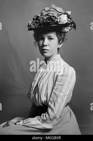 Belle jeune femme portant un chapeau à la mode des poses, ca. 1900. Banque D'Images