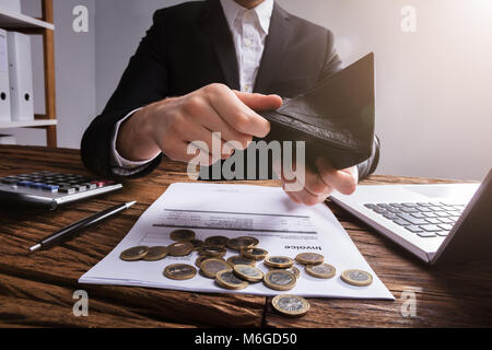 La main d'affaires Contrôle de portefeuille avec des pièces de monnaie et le projet de loi sur un bureau en bois Banque D'Images