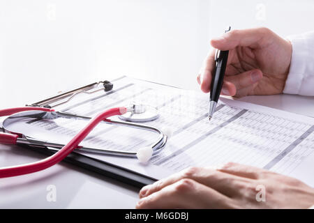 Close-up d'un stéthoscope près de main du médecin l'analyse Rapport sur le Presse-papiers Banque D'Images