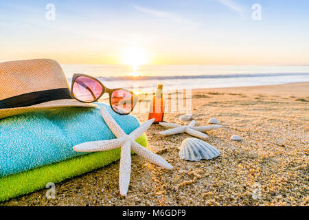 Accessoires d'été comme les lunettes, serviettes, chapeau, crème solaire, de coquillages et d'étoiles de mer sur la plage de sable au Portugal Banque D'Images