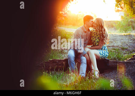 Un couple aimant se regarder dans les derniers rayons du soleil, dans un champ près de la route. Banque D'Images