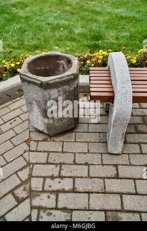 Banc de rue en béton et poutres en bois se dresse à côté d'une poubelle en béton dans le parc public Banque D'Images