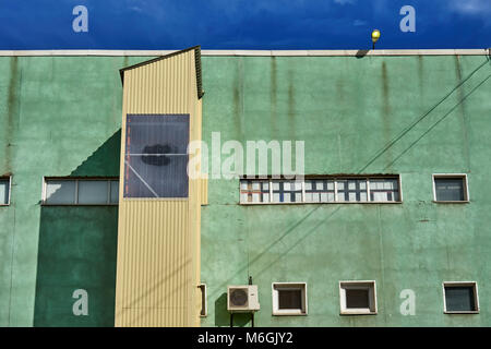 Bâtiment industriel à la façade verte face à un ciel bleu Banque D'Images