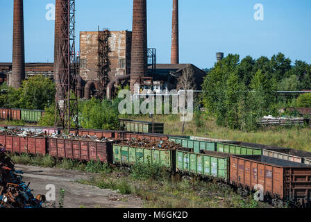 Complexe industriel abandonné, avec de grandes cheminées altérées surplombant les bâtiments délabrés contre un ciel bleu clair Banque D'Images