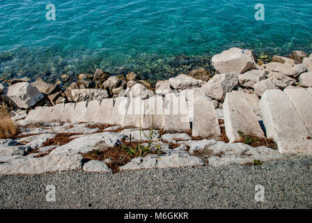 Vue sereine sur les marches en pierre grossière descendant dans l'eau bleue fascinante de l'océan. De grands rochers bordent les marches et sont répartis sur le fond de la mer Banque D'Images