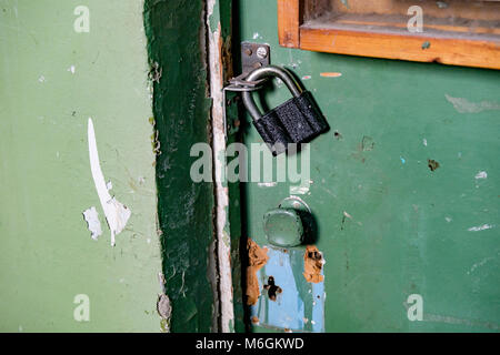 Nouveau cadenas sur l'ancienne porte verte dans l'entrée d'un immeuble ancien Banque D'Images