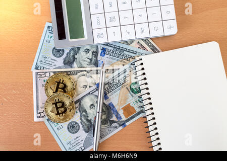 Deux golden bitcoins, journal, stylo, calculatrice et sur le dollar US Vue de dessus Banque D'Images