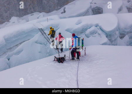 Un groupe de grimpeurs traversant une crevasse sur une échelle, l'Island Peak, Région de l'Everest, au Népal Banque D'Images