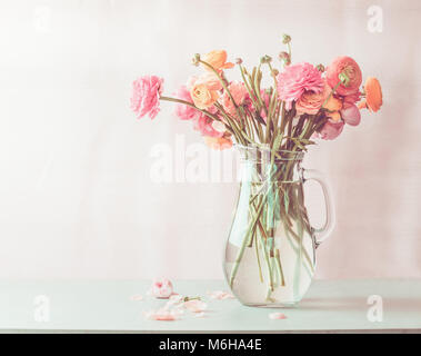 Pastel pink ranunculus fleurs bouquet dans la verseuse en verre sur la table, vue avant Banque D'Images