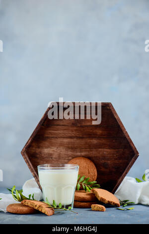 Petit-déjeuner sain concept avec biscuits, un verre de lait, un plateau en bois et feuilles de pistache sur un fond noir en gris clair. Maison savoureux p Banque D'Images