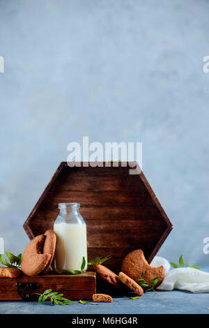 Petit-déjeuner sain concept avec biscuits, une bouteille de lait, un plateau en bois et feuilles de pistache sur un fond noir en gris clair. Maison savoureux Banque D'Images