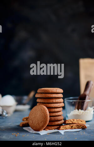 Pile de cookies de sucre sur un arrière-plan en pierre avec ingrédients hors focus. Concept de cuisson sur un fond sombre avec copie espace. Banque D'Images