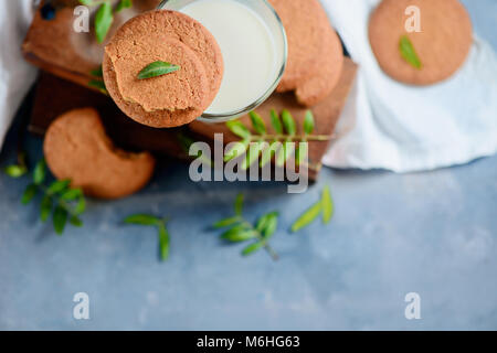 Des biscuits avec de minuscules feuilles vertes sur fond noir en un décor avec des caisses en bois et de linge blanc serviette. La mise à plat du printemps avec l'exemplaire de l'espace. Banque D'Images