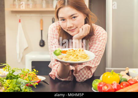 Happy young asian woman holding fièrement sa cuisine suite, jambon et fromage plat de spaghetti cabonara, bon pour la cuisine maison concept, le ton des couleurs vintage Banque D'Images