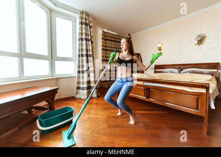 Femme des danses et chante pendant le nettoyage, dans ses mains une rdp pour laver les planchers. Banque D'Images