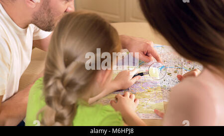 Heureux père, mère et fille à la loupe par carte à Banque D'Images