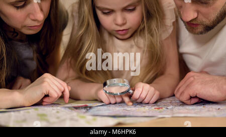 Les parents apprendre la géographie avec sa fille, l'étude de la carte par l'intermédiaire de loupe Banque D'Images