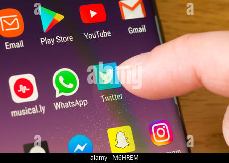 Gros plan de l'application Twitter sur un smartphone sélectionné par le doigt d'une femme pointant vers l'application sur le écran du téléphone cellulaire Banque D'Images