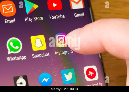 Gros plan de l'application Instagram sur un smartphone sélectionné par le doigt d'une femme pointant vers l'application sur le écran du téléphone cellulaire Banque D'Images